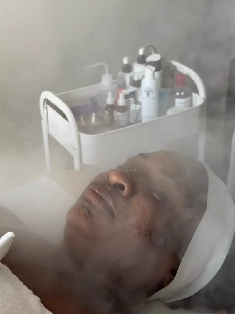 Steam facial in the studio with a skincare product cart behind